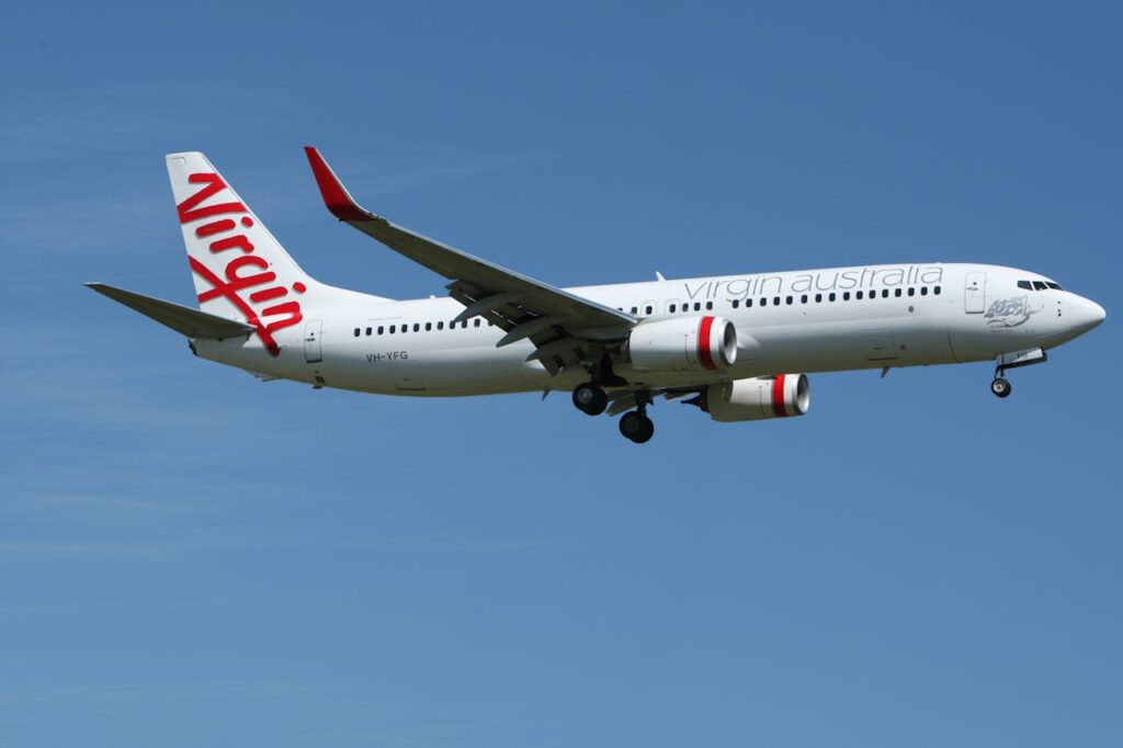 Virgin Australia aircraft approaching landing at Melbourne Airport under clear blue skies.