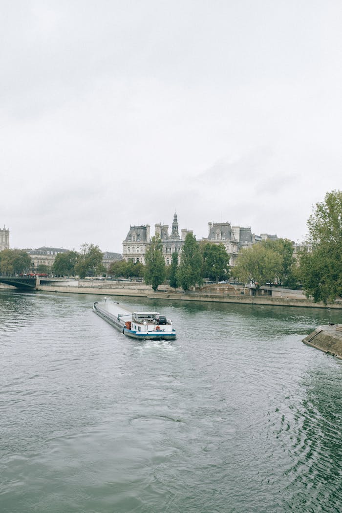 Scenic view of a boat on the Seine River with classic Parisian architecture in the background.